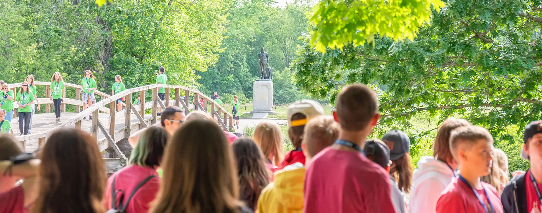 A group of students stand in front of a statue in a park in Boston.