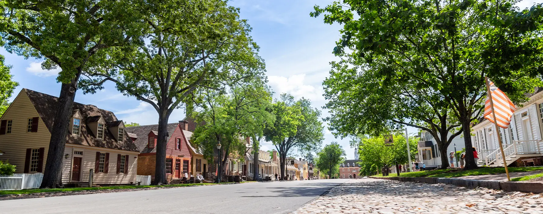 A photo taken in the middle of a street with older style houses on each side.