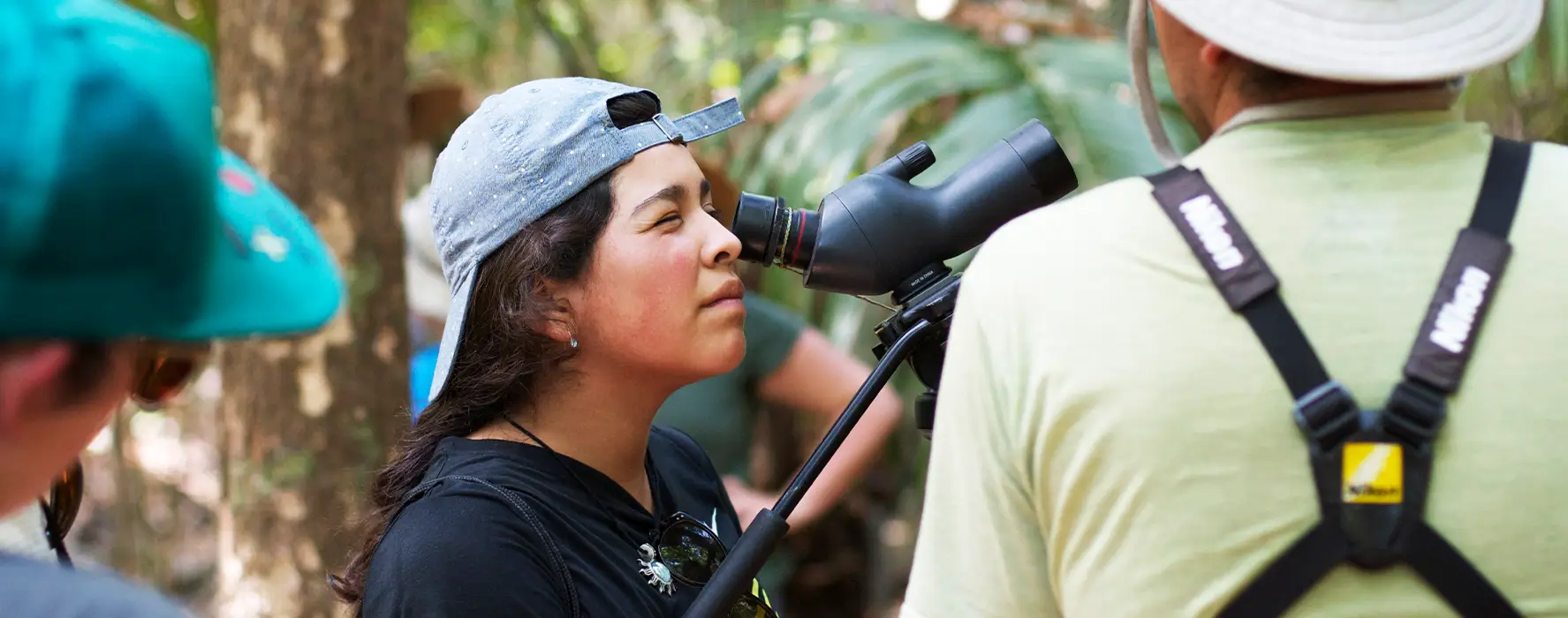 A student with one eye closed, looking through a monocular.